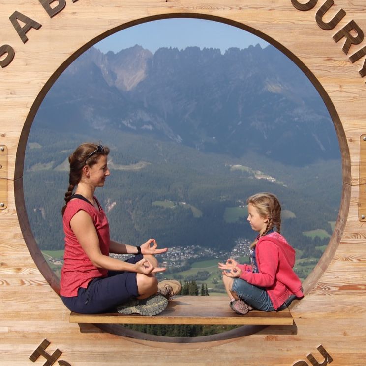 Mutter und Kind im Lotussitz vor Bergpanorama